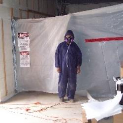 This construction worker is dressed in a proctective suit due to the removal of material containing asbestos from the site. (November 12, 2007)